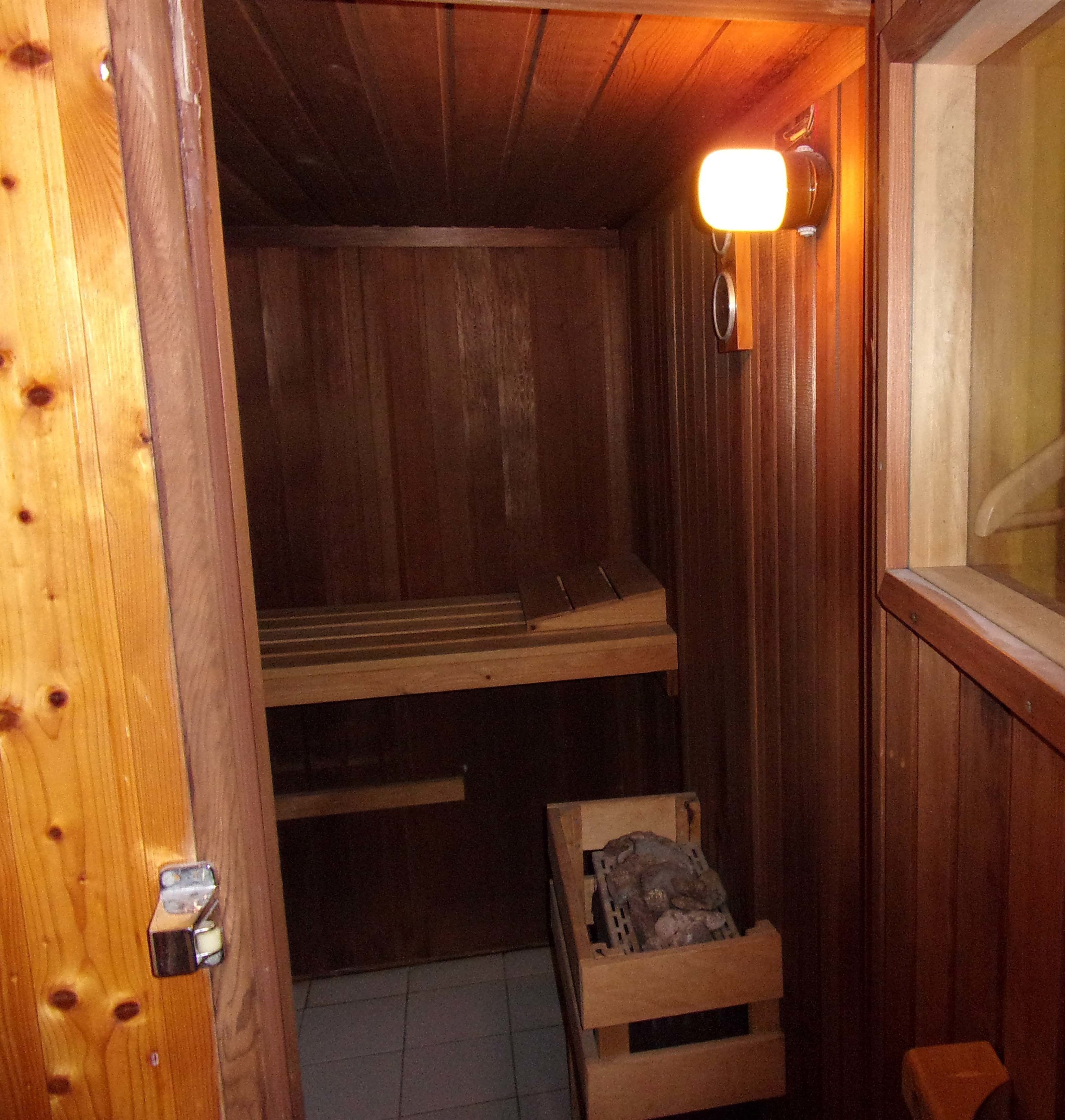 A wooden sauna with a bench and a small wooden crate, likely for towels or personal items.