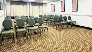 Une salle de conférence avec des rangées de chaises vertes et un tapis à motifs.