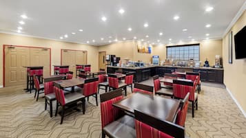Un comedor de hotel con varias mesas y sillas, una estación de buffet y un ventanal grande.
