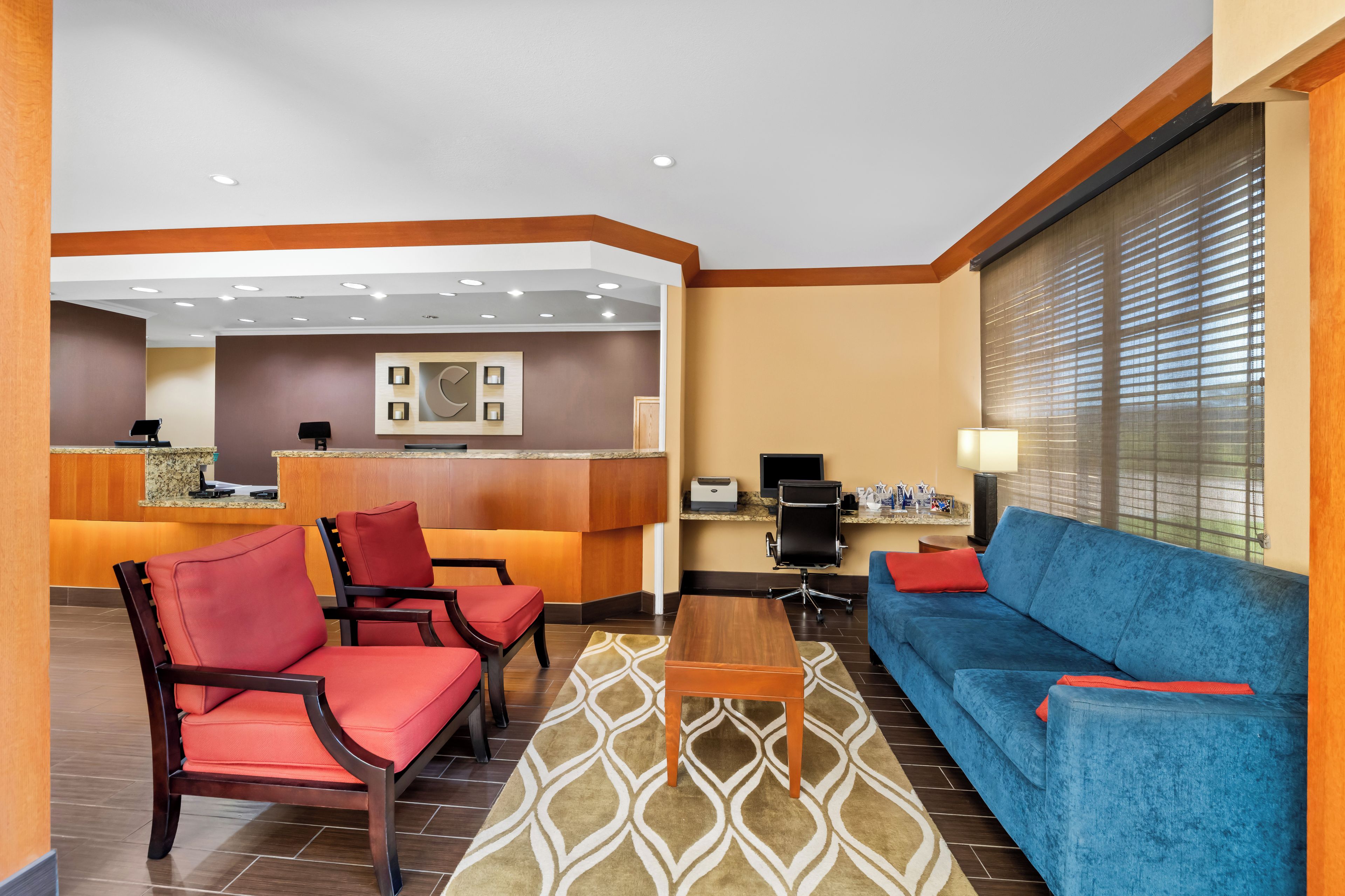 A hotel lobby with a reception desk, seating area, and a sofa.