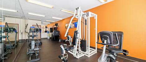 Un gimnasio con diversos equipos de ejercicio, incluyendo cintas de correr, elípticas y máquinas de pesas.