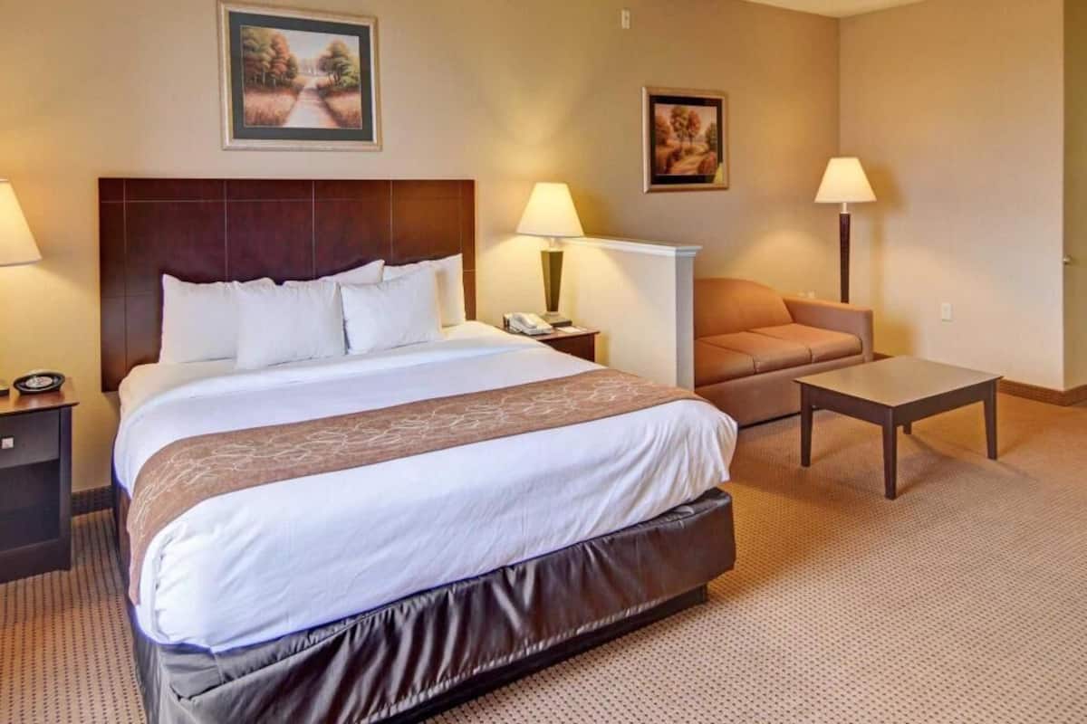 Een hotelkamer met een groot bed, nachtkastjes, een bureau, een stoel en twee wandlampen.
