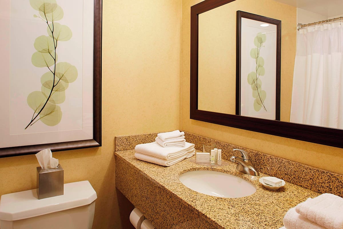A bathroom with a granite countertop, a sink, a mirror, and a toilet.