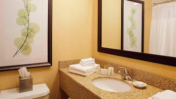 A bathroom with a granite countertop, a sink, a mirror, and a toilet.