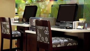 Escritorio con dos monitores, un teclado y un ratón. Dos sillas con cojines estampados.