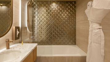 Een moderne badkamer met een bad, een douche met glazen wanden en een marmeren wastafelblad.