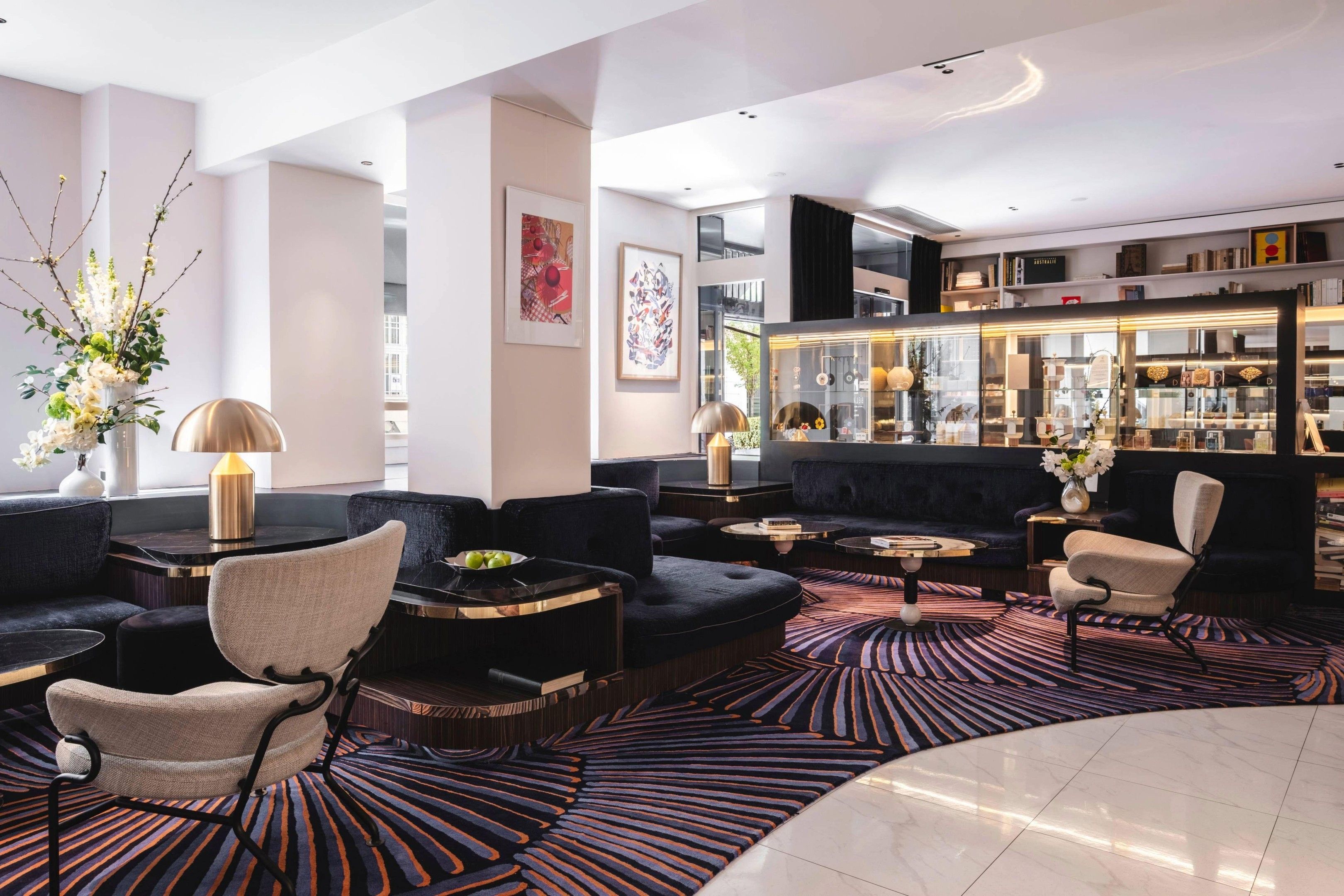 A modern lounge area with sofas, chairs, a coffee table, and a patterned carpet.