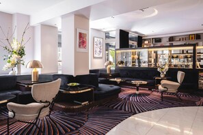 A modern lounge area with sofas, chairs, a coffee table, and a patterned carpet. - Hotel Bel Ami (Paris)
