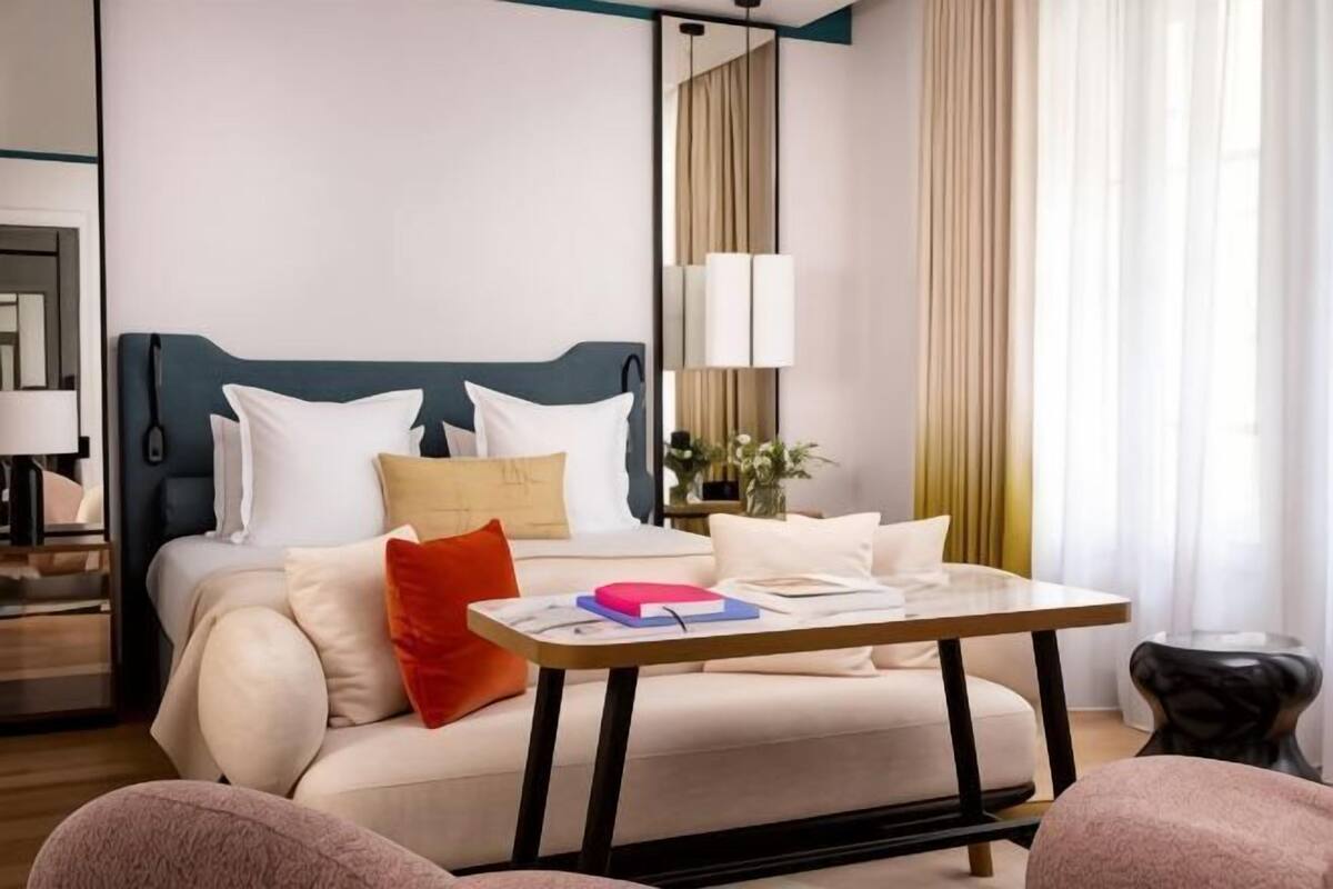 A modern hotel room with a bed, bedside table, and a view of the outside.