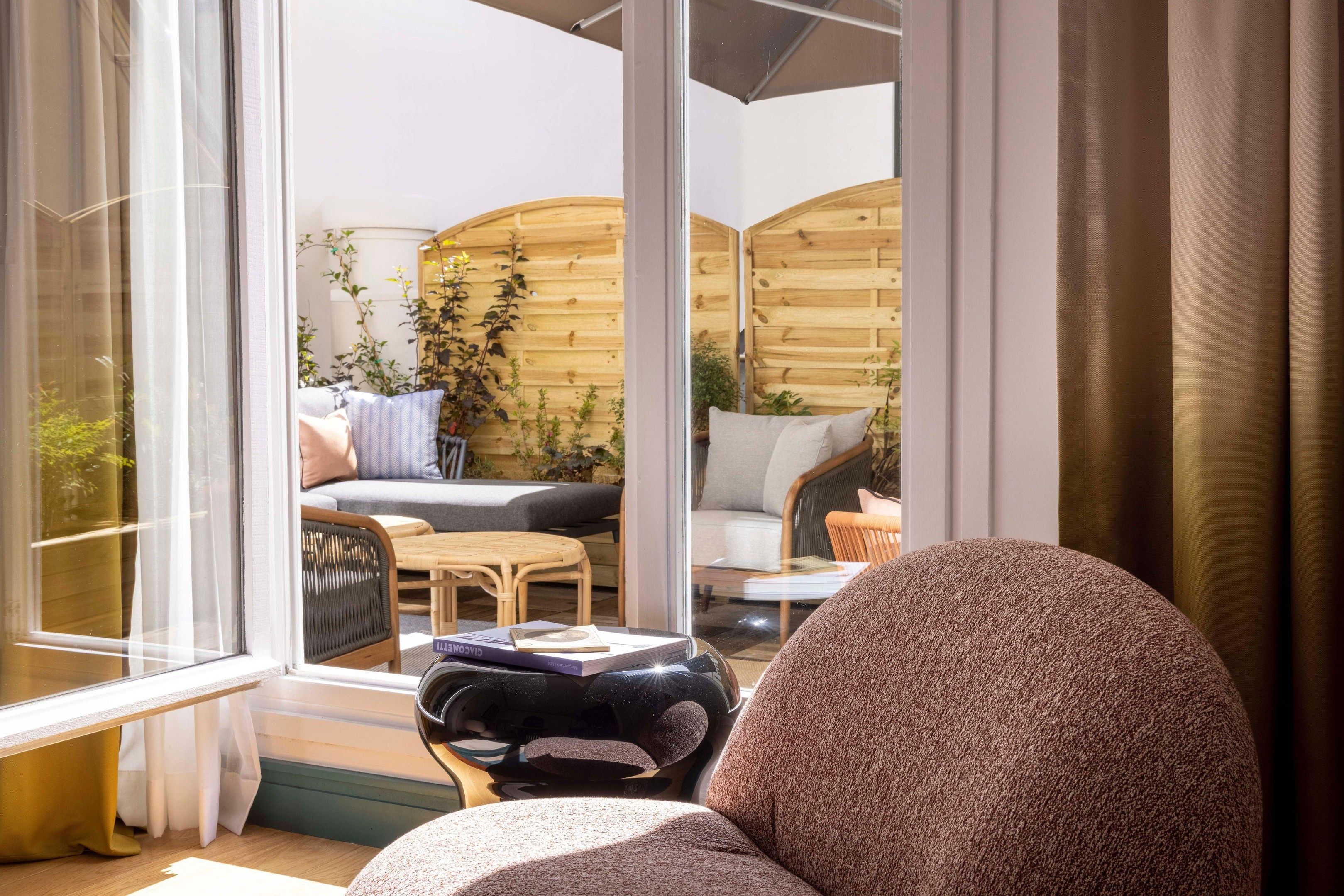 A room with a large window, a sofa, a table, and a chair.