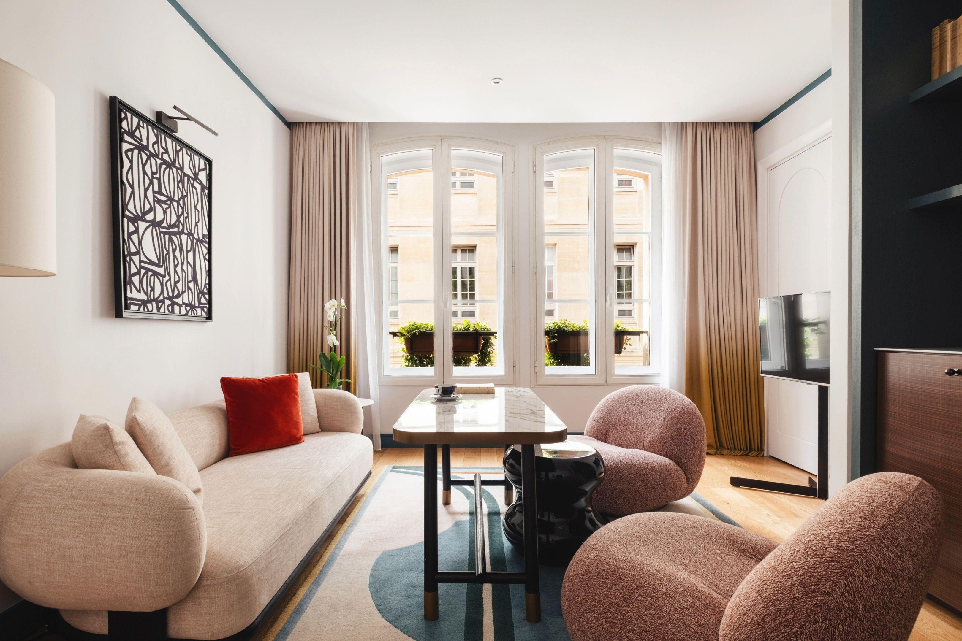 Ein modernes Wohnzimmer mit einer Couch, Sesseln, einem Couchtisch und einer TV-Konsole.