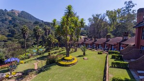 A resort with multiple bungalow-style buildings, a well-maintained lawn, and a mountainous backdrop.