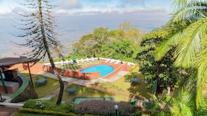 A pool area with lounge chairs and a view of the landscape.