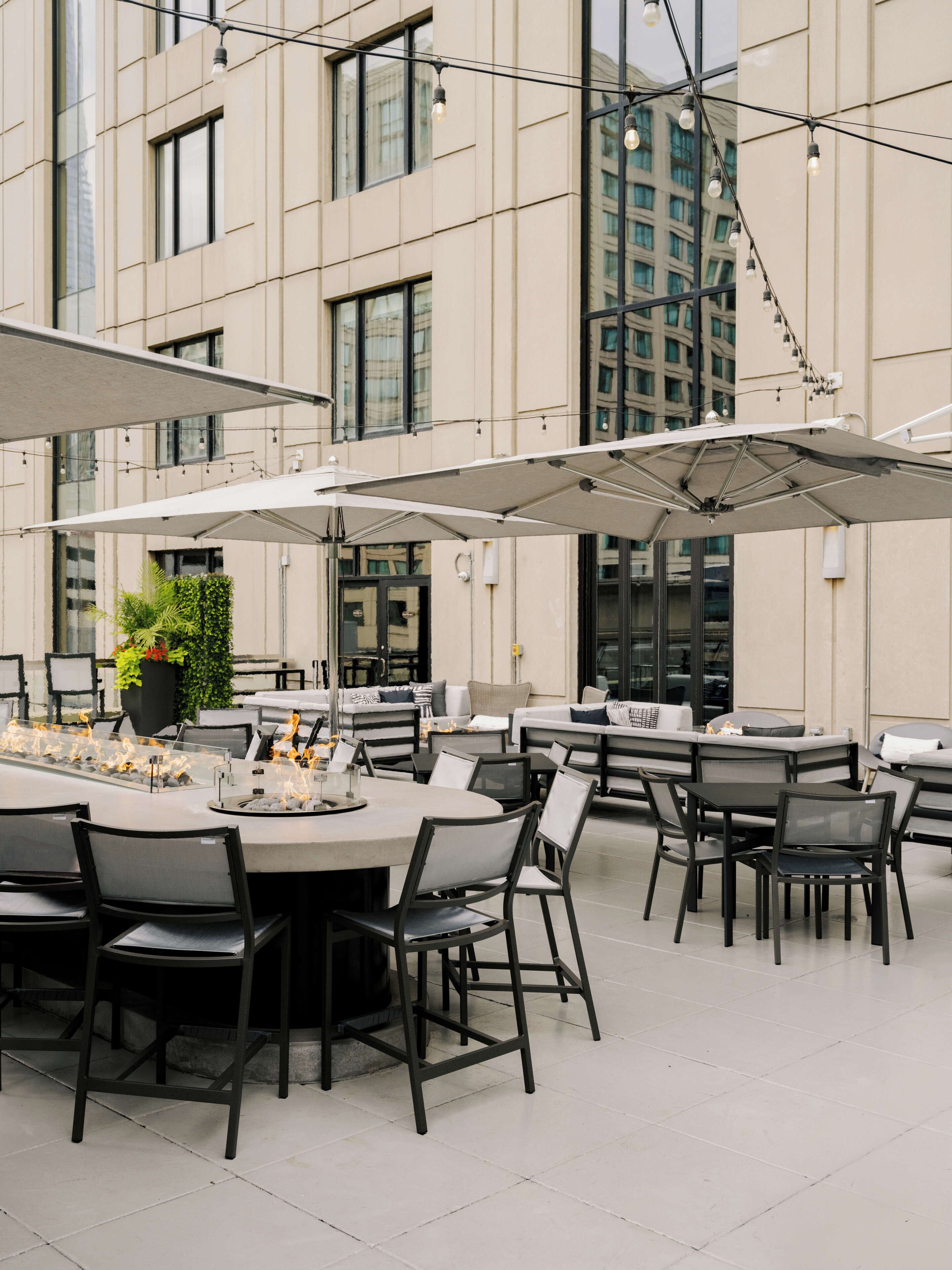 Un espace extérieur aménagé pour les repas, avec des tables et des chaises, des parasols et un pot de fleurs.