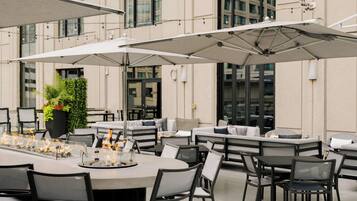 Un espace extérieur aménagé pour les repas, avec des tables et des chaises, des parasols et un pot de fleurs.