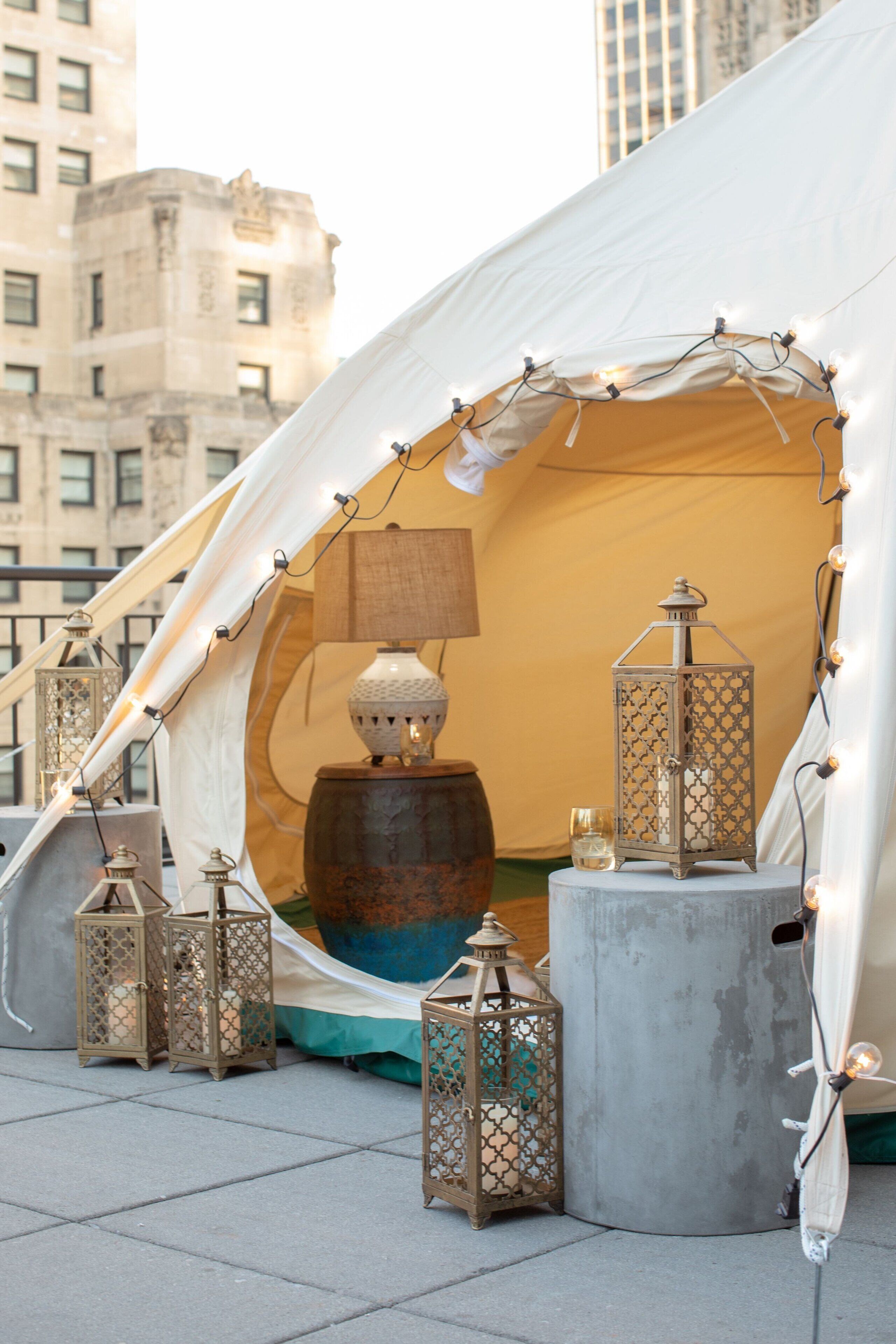 A tent with string lights, lanterns, and a lamp.