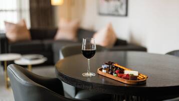 Una mesa de comedor con una copa de vino tinto, una bandeja de fruta y una mesa de madera oscura.