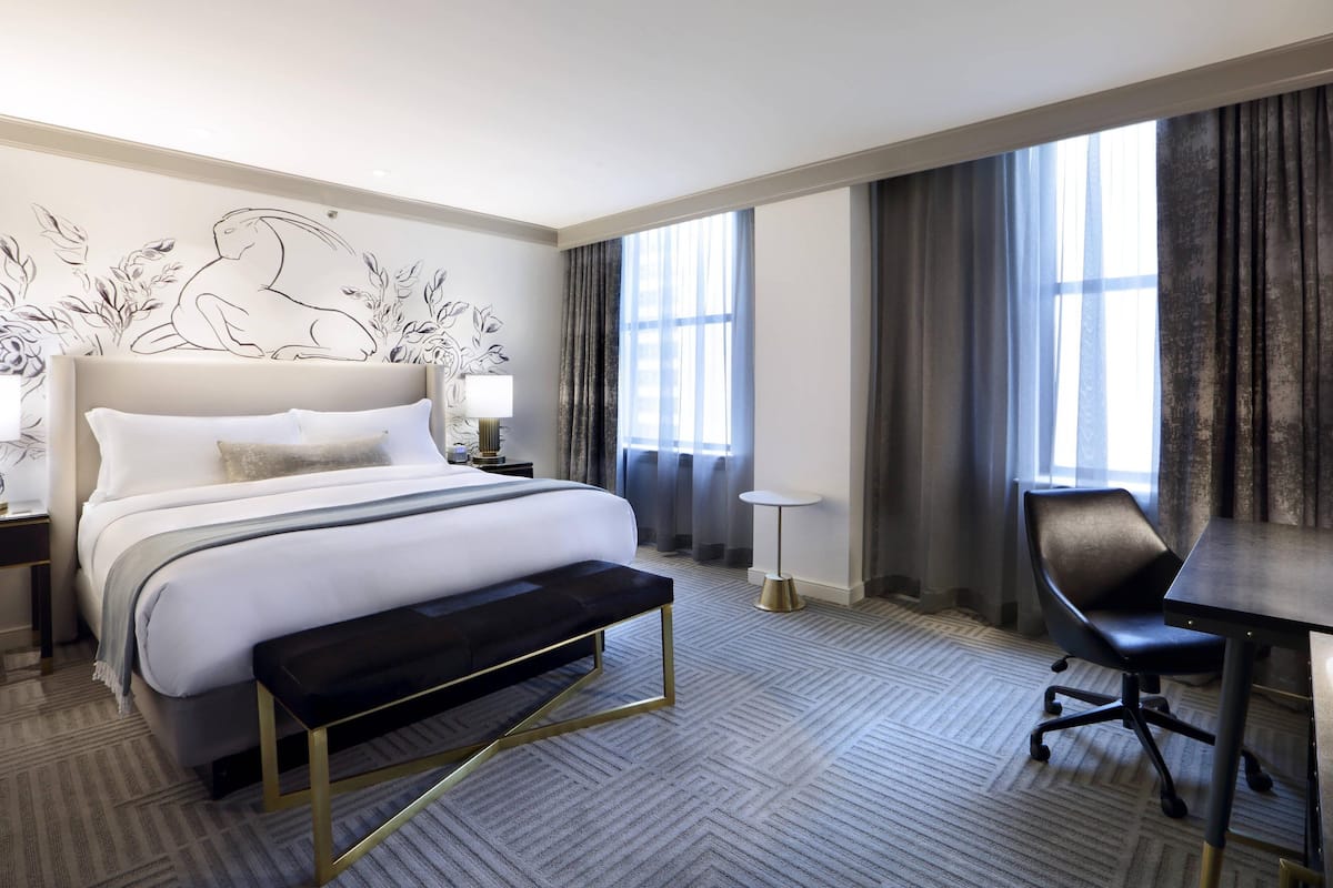 Una habitación de hotel con una cama grande, un escritorio, una silla y una mesita.