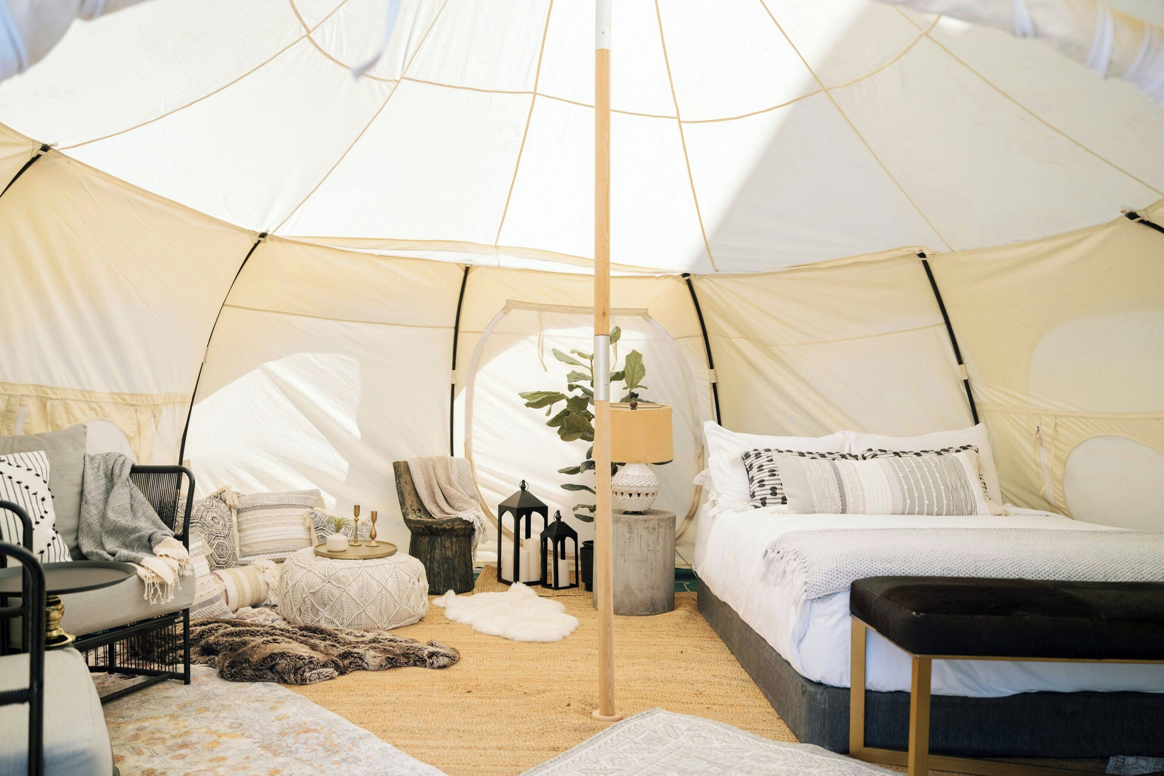 Ein Zeltinnenraum mit Bett, Sitzecke, Lampe und Dekoration.