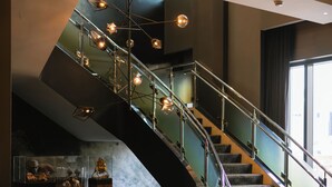 A modern staircase with glass railings and pendant lighting.