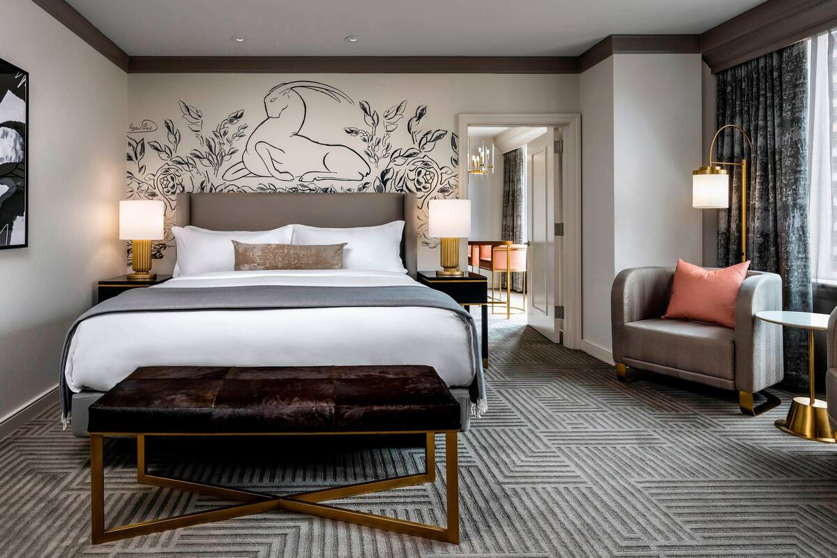 Una habitación de hotel moderna con una cama grande, un banco, un sofá y una mesita.