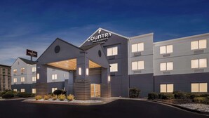 Um hotel moderno com uma placa de destaque 'Country Inn & Suites', apresentando um design contemporâneo com grandes janelas e uma entrada bem iluminada.