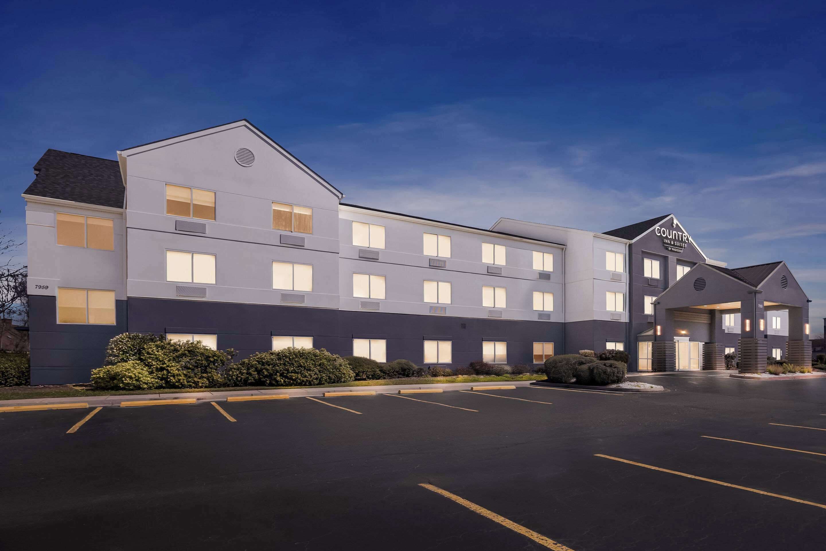 A multi-story hotel with a modern design, featuring a parking lot in front.