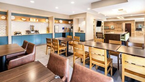 Restaurante moderno com mesas e cadeiras de madeira, área de cozinha e espaço com balcão.