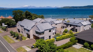 A residential area with modern houses, a clear view of the sea, and a distant mountain range.