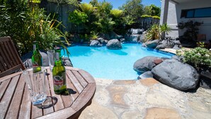 A pool area with a wooden table, two beer bottles, and a glass.