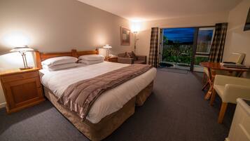 A hotel room with a large bed, bedside tables, a desk, and a view of the outdoors.