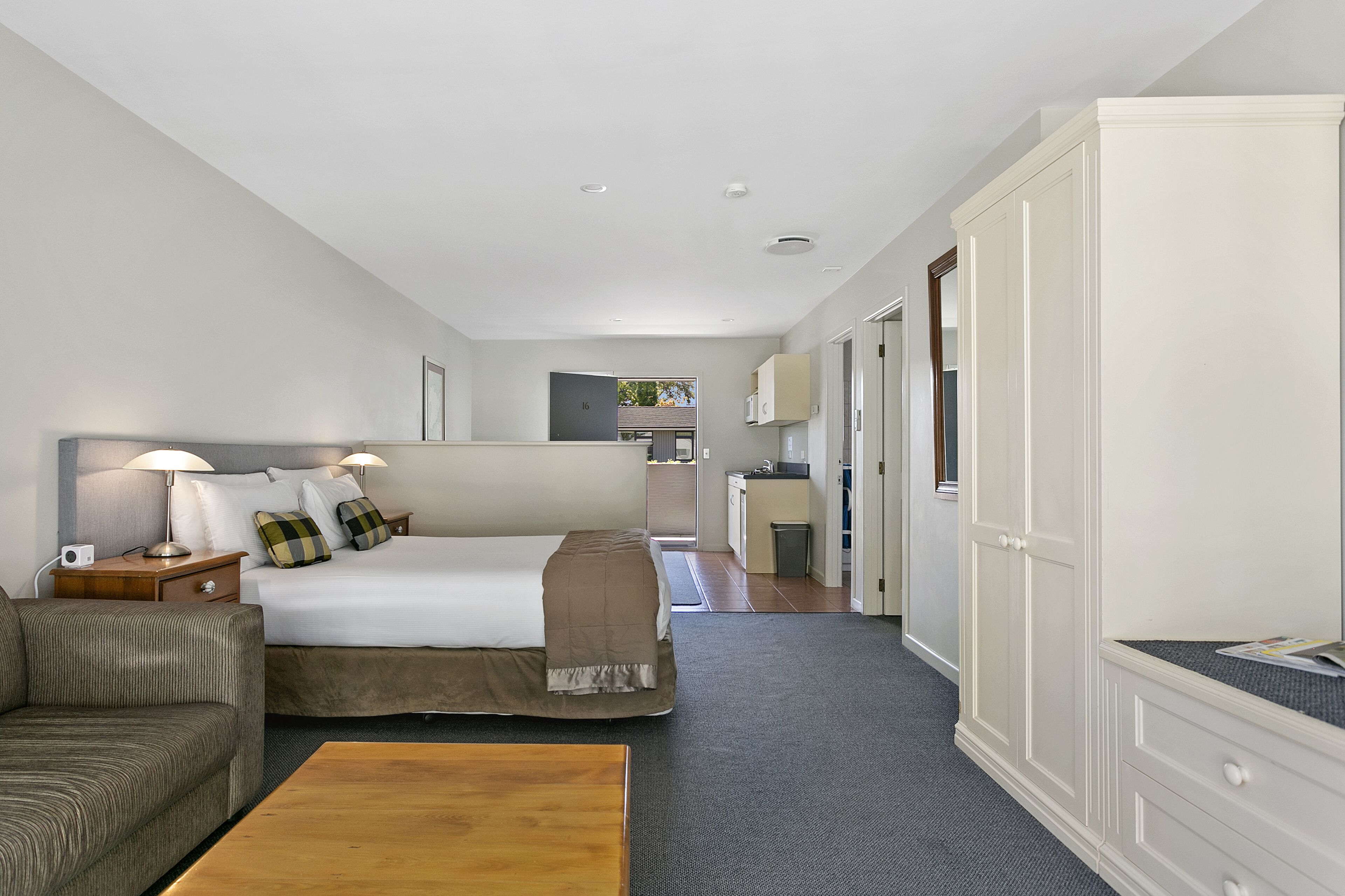 A hotel room with a bed, a sofa, a desk, and a wardrobe.