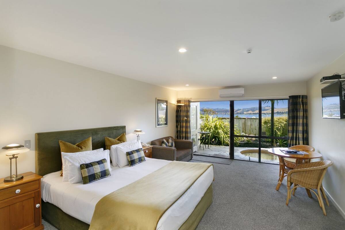 A hotel room with a bed, a desk, a chair, and a view of the outdoors.