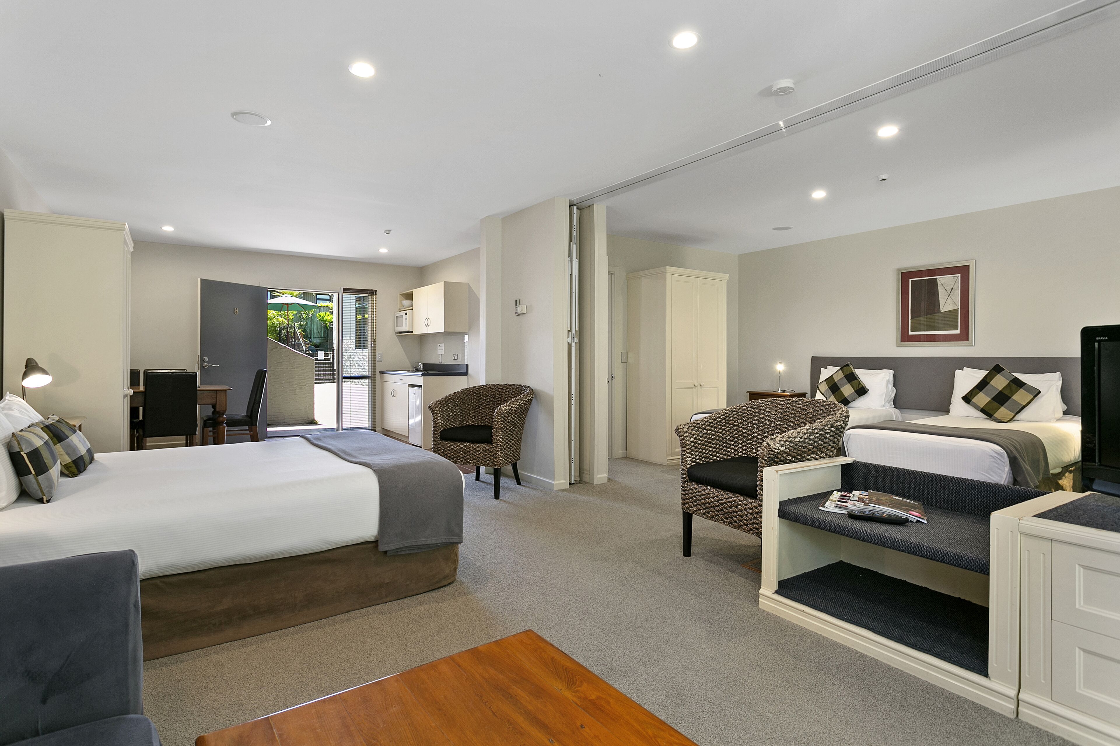 A hotel room with a bed, a desk, a chair, and a sofa.