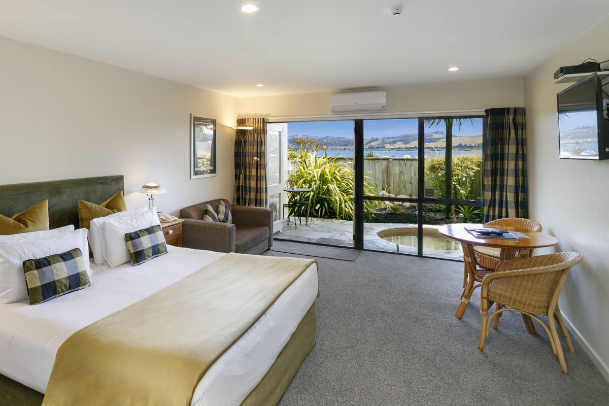A bedroom with a large bed, a desk, and a view of the outdoors.