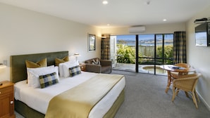 A bedroom with a large bed, a desk, and a view of the outdoors.