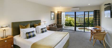 A bedroom with a large bed, a desk, and a view of the outdoors.