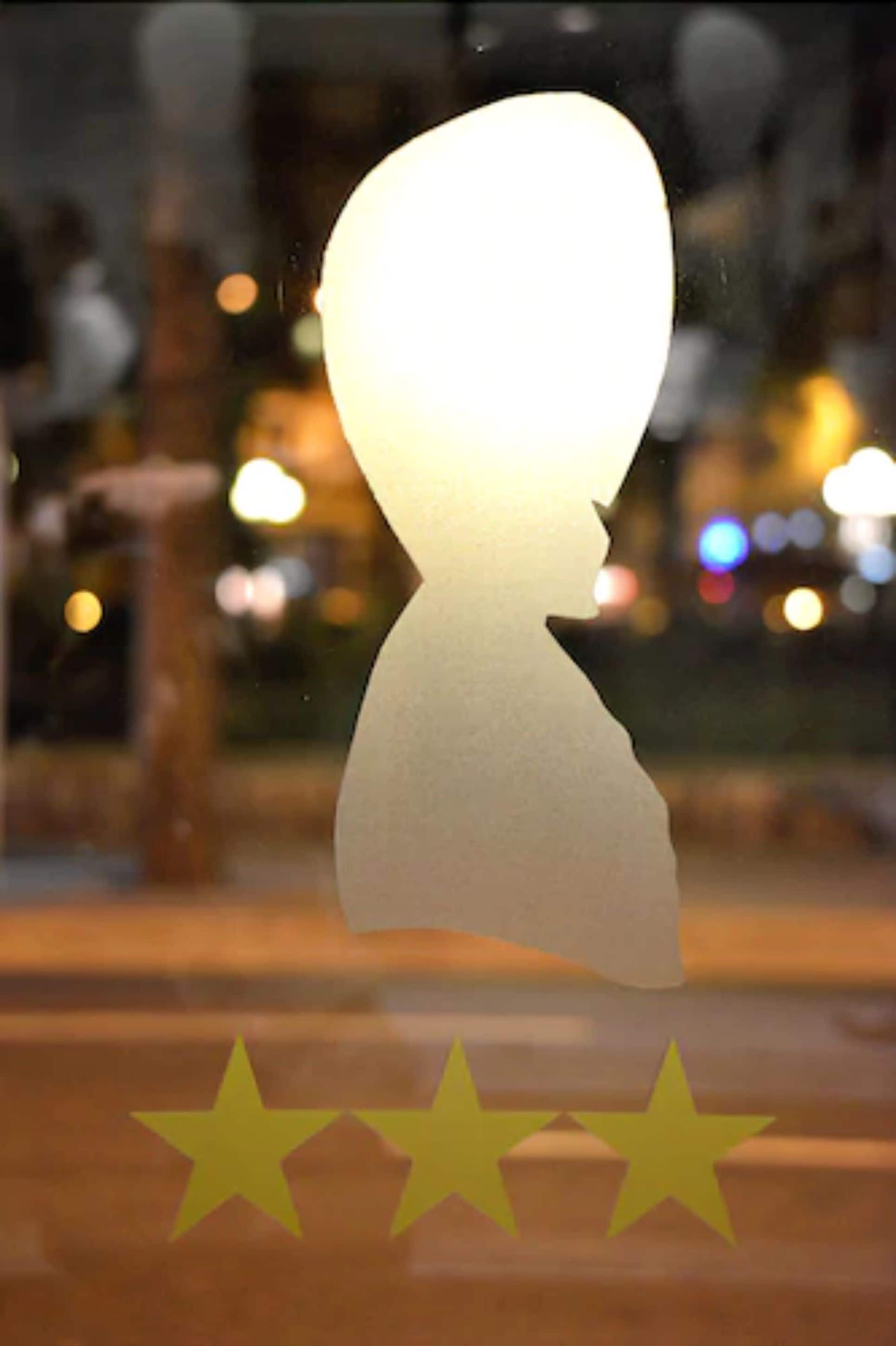 A silhouette of a person with a light bulb head, three stars below, and a blurred background with lights.