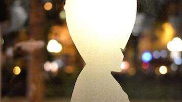 A silhouette of a person with a light bulb head, three stars below, and a blurred background with lights.