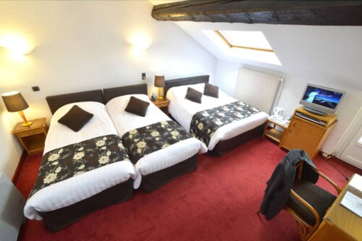 Une chambre avec deux lits, un bureau, une chaise, une télévision et une lucarne.