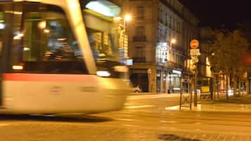Una strada cittadina di notte con un tram in movimento.