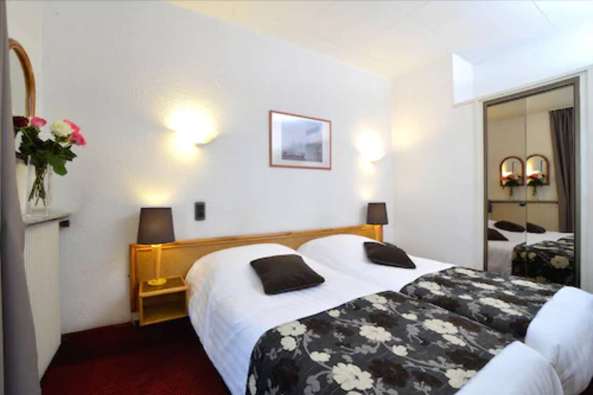 Une chambre d’hôtel avec un lit, des lampes de chevet, un tableau encadré au mur et un miroir dans un coin.