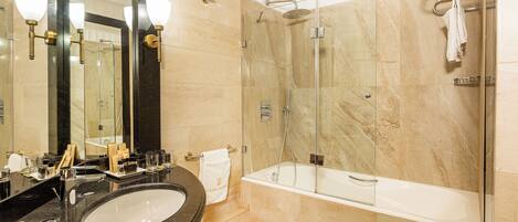 Un baño con un lavabo de granito negro, ducha con mampara de vidrio y bañera blanca.