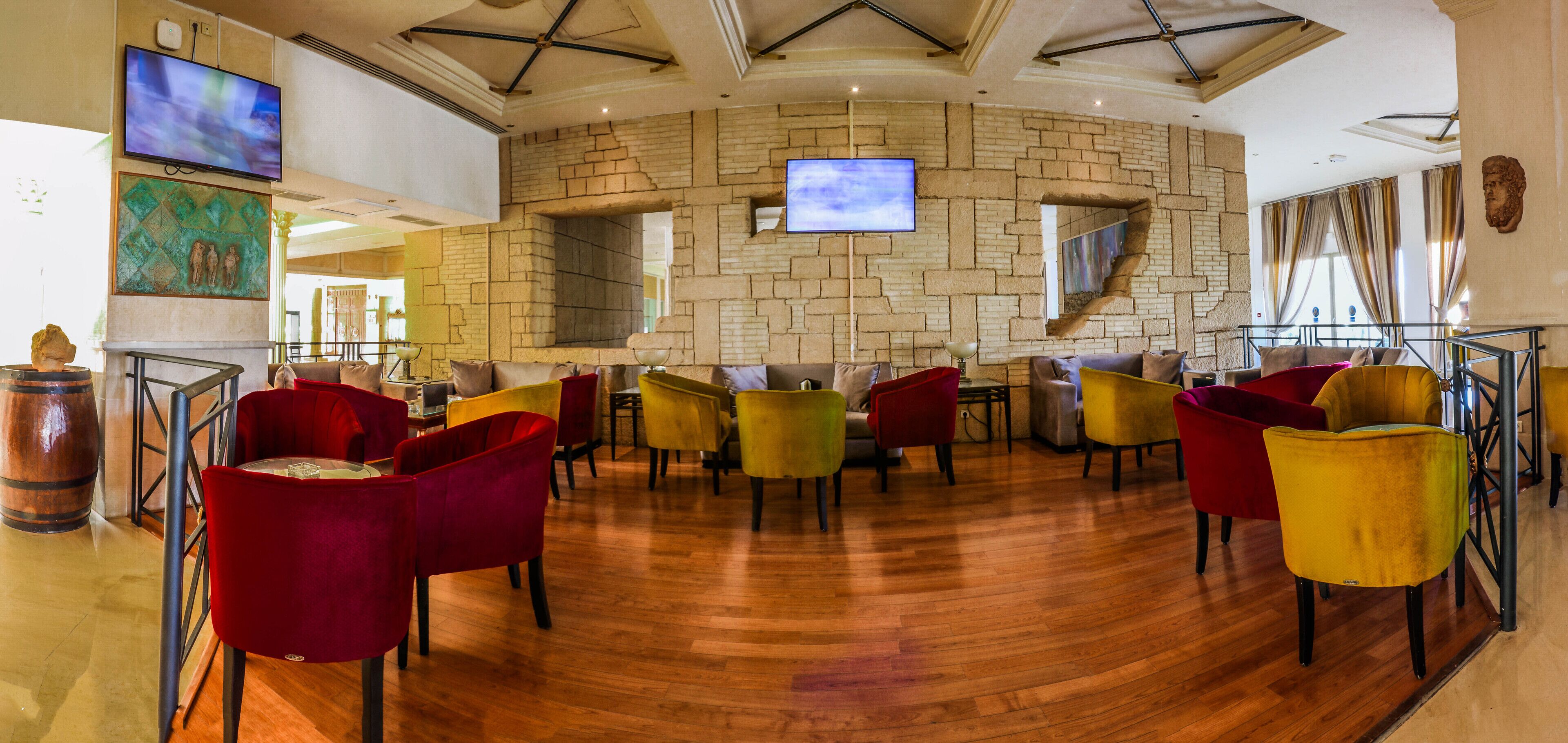 A restaurant with a brick wall, multiple TVs, and colorful chairs.