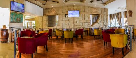 A restaurant with a brick wall, multiple TVs, and colorful chairs.