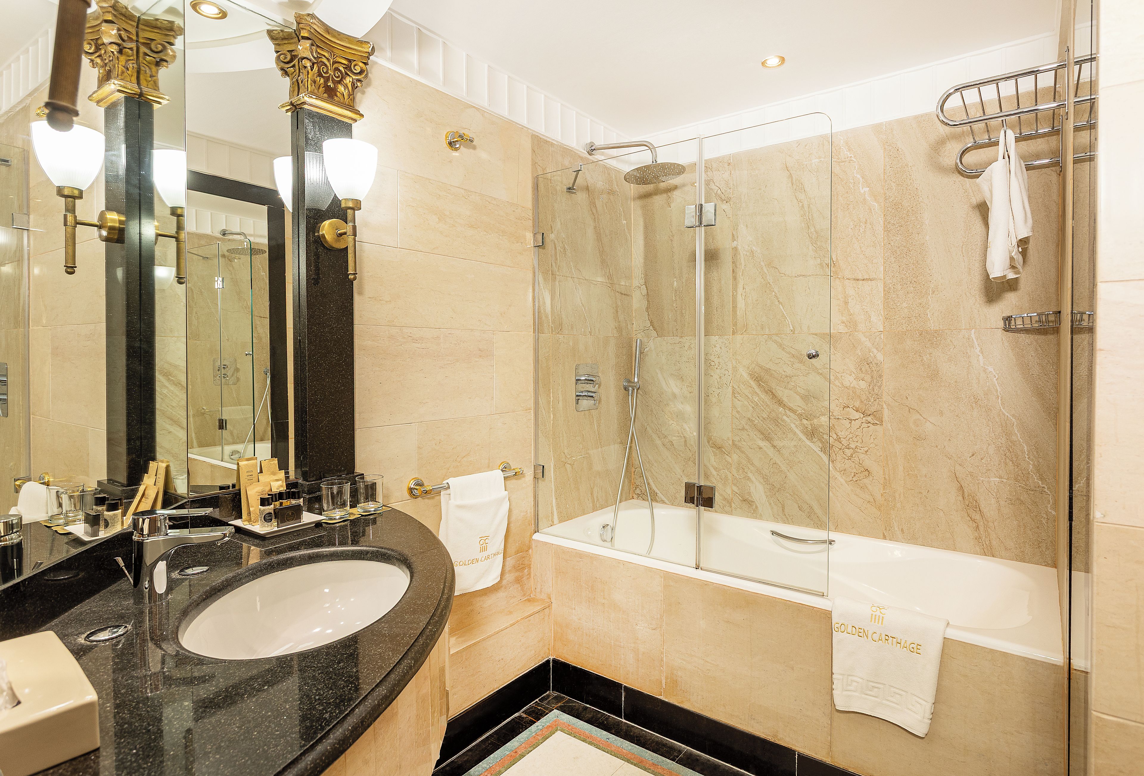 Un baño moderno con ducha envuelta en vidrio, bañera y tocador con lavamanos.