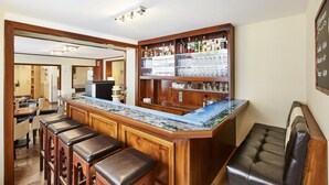 A bar area with a wooden counter, bar stools, and shelves stocked with bottles and glasses. - Hotel Imperial (Munich)