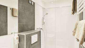 Une salle de bain moderne équipée d’un lavabo, de toilettes et d’une douche.