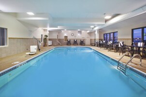Piscina com área de estar, cadeiras e um relógio na parede.