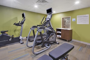 A fitness center with treadmills, a stationary bike, and a bench.